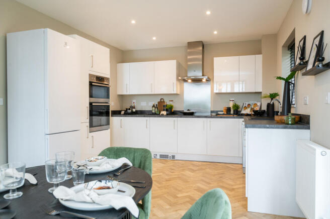 A modern kitchen with white cabinets and stainless steel appliances is visible in the background