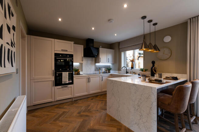 A modern kitchen with a marble island and bar stools in the foreground
