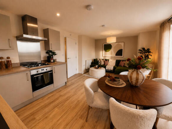 A modern kitchen with a dining table in the foreground transitions into a cozy living room with a so