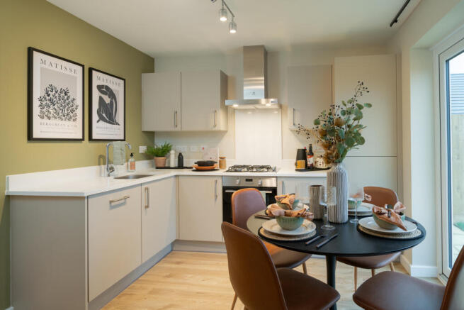 A modern kitchen with a dining table set for a meal in the foreground and a sleek