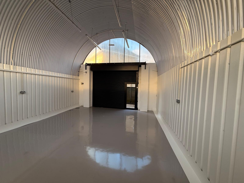 An empty arch with white lining and full height glazing to the front.